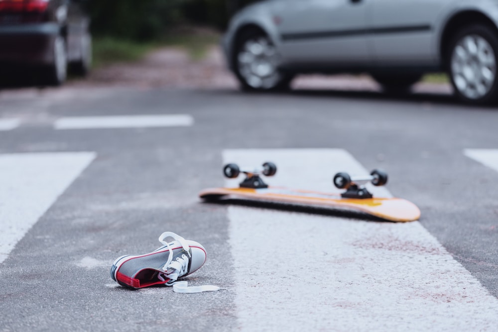 What Not To Say To Your Insurance Company 3 Skateboard and shoe lying on a crosswalk with a car stopped in the background