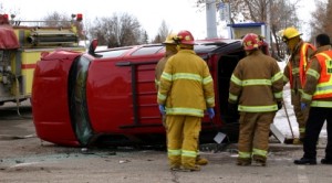firefighters standing near a rollover crash