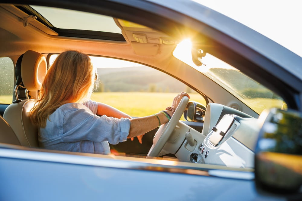Woman driving a rental car on a road at sunset