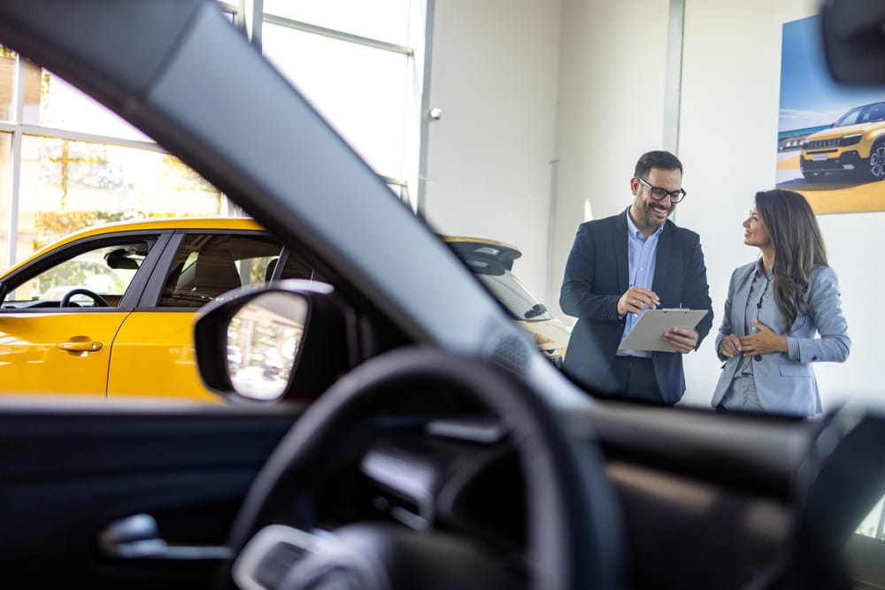 Rental agent reviewing paperwork with a customer next to a rental car