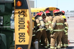 Firemen standing near tipped school bus