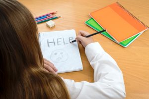 photo illustration of child abuse a schoolchild sits at a desk asking for help by a written message