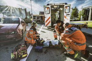 Paramedics providing first aid to man injured in car accident