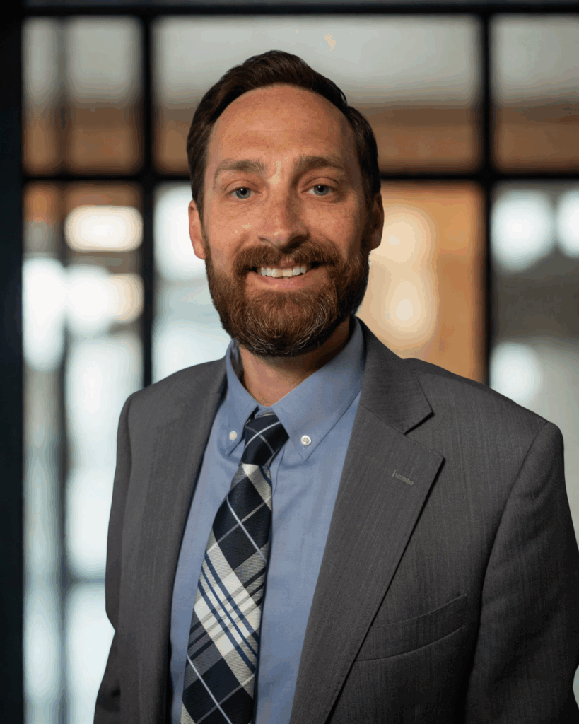 Attorney Nate Lawyer 1 Cyrus Nate Lawyer headshot with smile, grey suit, plaid tie. Carr & Carr Injury Attorneys
