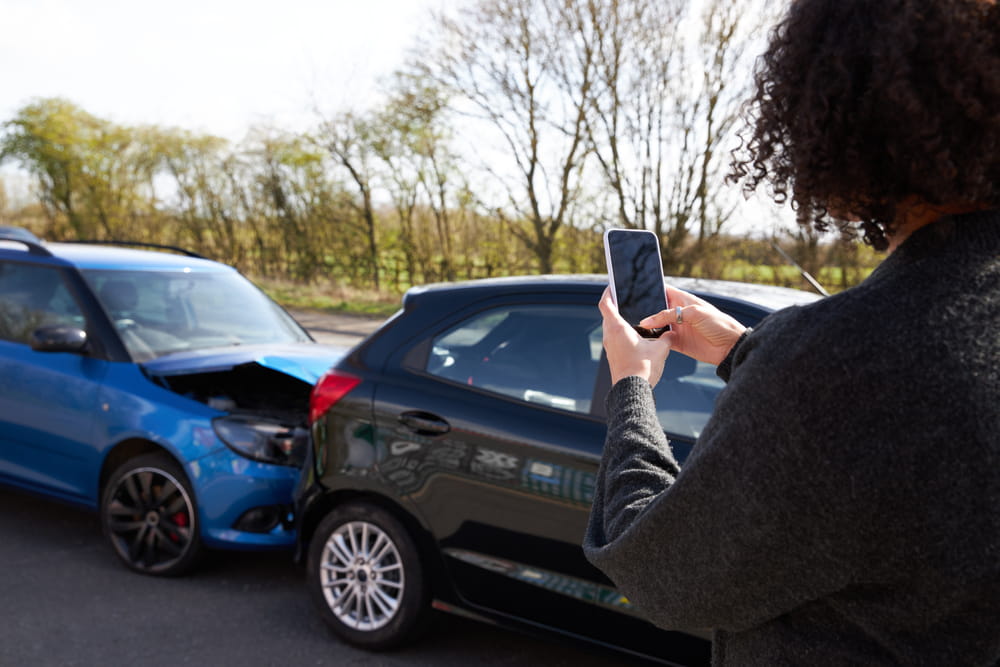 Person taking photos of car accident damage for insurance documentation