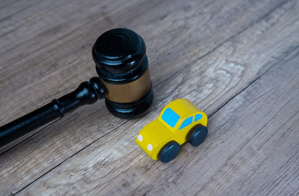 Gavel next to a toy car representing legal liability and settlement decisions after a car accident