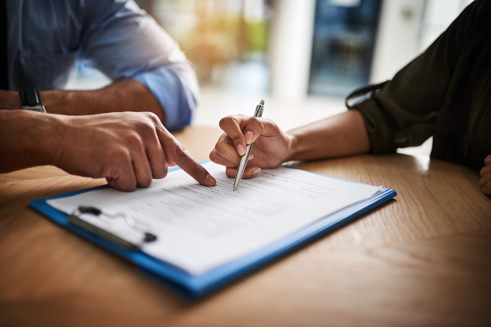 Two people reviewing and pointing at a document on a clipboard