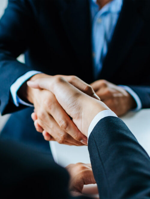 A lawyer and a client handshaking over a table with documents